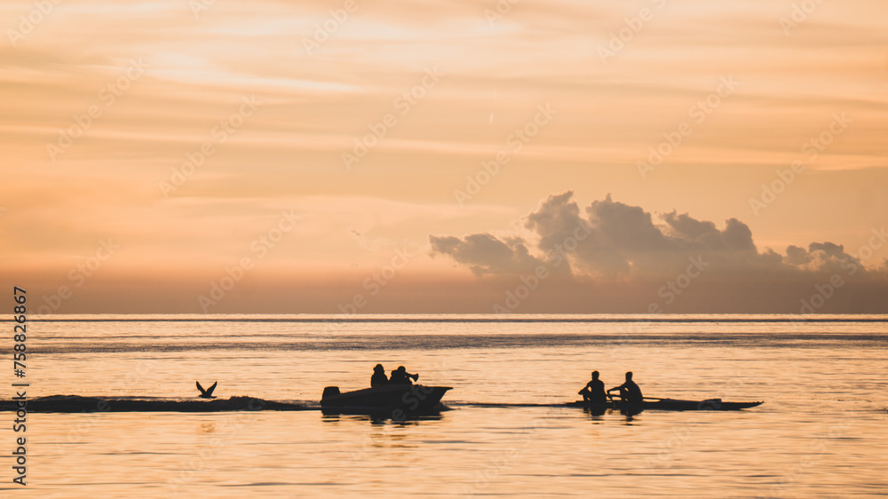 Two canoeists on one canoe sailing on the gulf of Trieste being followed by the instructor on another boat and a curious seagull all at sunset