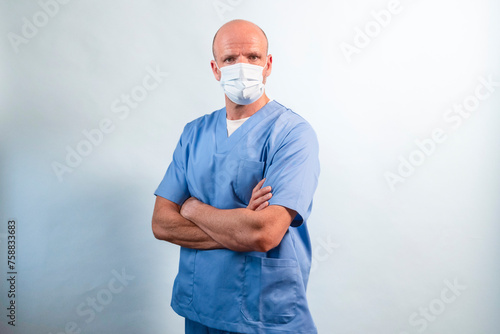 Portrait of a physiotherapist in light blue gown and face mask looking at camera in studio.