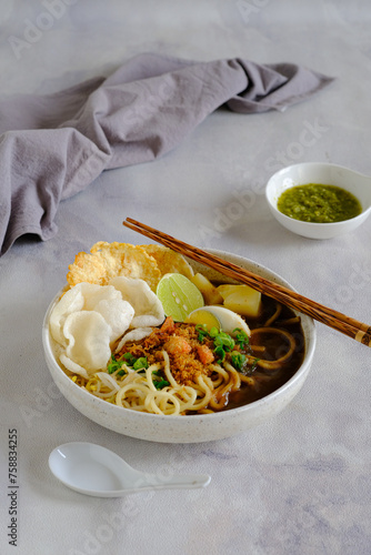 emie, Indonesian noodle with shrimp broth, dry shrimp, , fried onion,onion leaves, bolied potatoes, egg and crackers photo