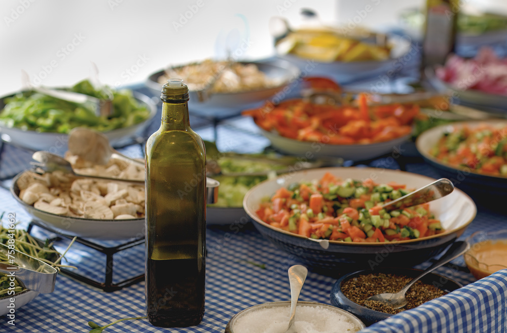 Dining setting with various dishes on a blue and white checkered tablecloth. A bottle of olive oil is centrally placed. The dishes are filled with colorful salads and fresh ingredients. Vegan dishes Dining setting with various dishes on a blue and white checkered tablecloth. A bottle of olive oil is centrally placed. The dishes are filled with colorful salads and fresh ingredients. Vegan dishes
