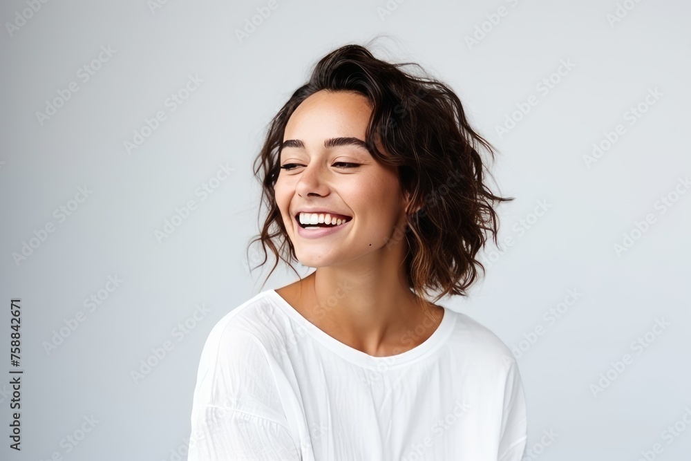 Portrait of a beautiful young woman laughing and looking up against grey background Portrait of a beautiful young woman laughing and looking up against grey background