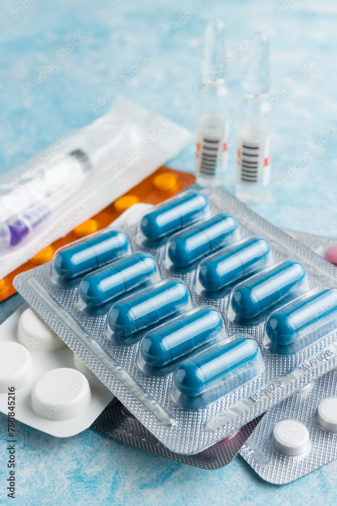 Pile of various capsules, pills and tablets in a blister pack on blue background, healthcare and medicine concept Pile of various capsules, pills and tablets in a blister pack on blue background, healthcare and medicine concept