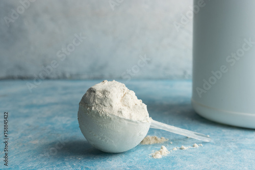 Whey protein powder in measuring spoon on a blue background photo