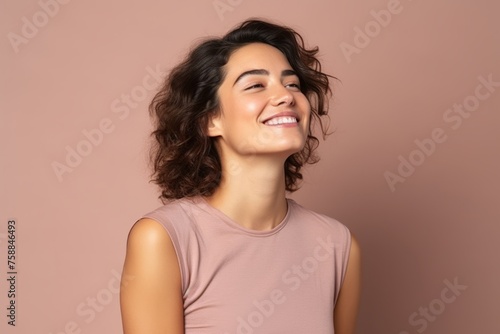 Portrait of a beautiful young woman smiling against a pink background. © Loli