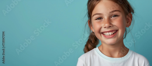 One smiling teeth happy young 10 yr old girl portrait long hair in braid lifestyle education wellness concept campaign isolated on blank blue studio background copy space fun caucasian Australian photo