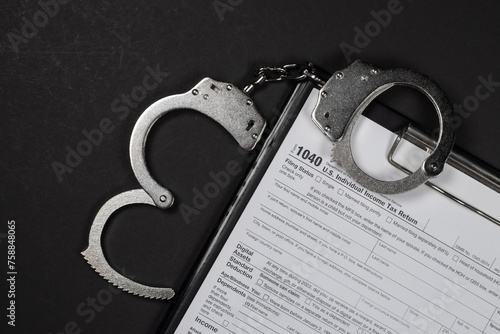 Income tax return documents and handcuffs. Tax evasion, crime and fraud concept. photo