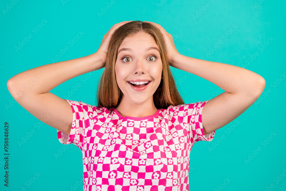 Photo portrait of pretty teenager girl hands touch head shocked wear trendy print pink clothes isolated on cyan color background Photo portrait of pretty teenager girl hands touch head shocked wear trendy print pink clothes isolated on cyan color background
