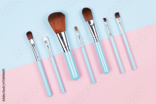 Set of makeup brushes on pink and blue colored composed background. Top view point, flat lay.