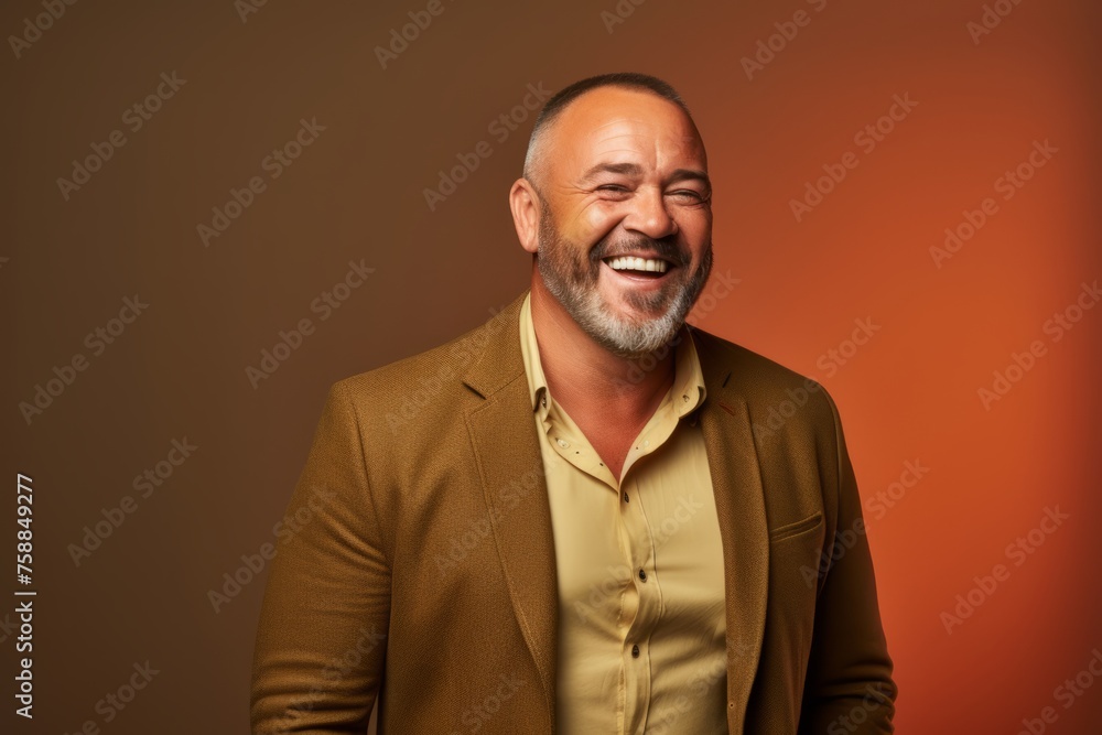 Handsome middle aged man laughing, on orange background. Studio shot.