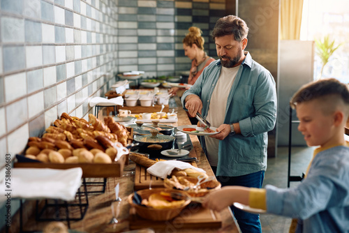Mature man having breakfast while being with his family in hotel. photo