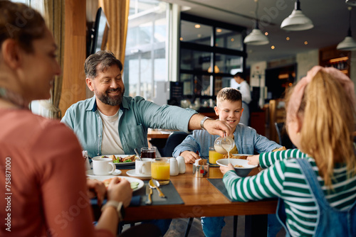 Happy man enjoying in breakfast with his family while staying in hotel.