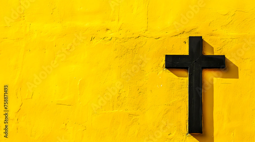 A black Christian cross on a yellow wall. Good Friday design concept with copy space photo