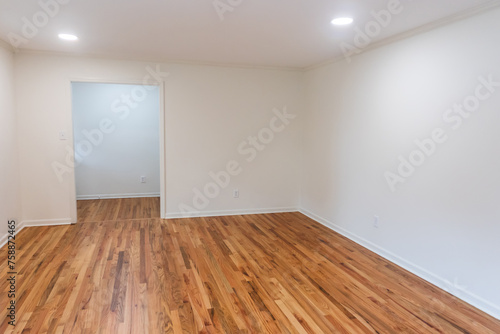 A house for sale with an empty white living room or den of a newly renovated and painted house with dark hardwood floors