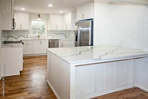 Light and bright newly remodeled white kitchen with quartz countertops, white shaker cabinets and gold hardware and stainless appliances