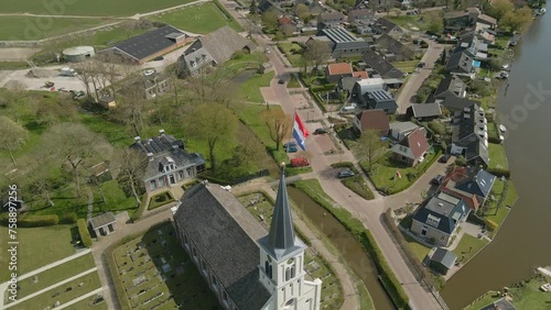 Aerial view of dutch flag on top of church (Johanneskerk) at sunny day during kingsday (Koningsdag), Oosthem, Friesland, Netherlands photo