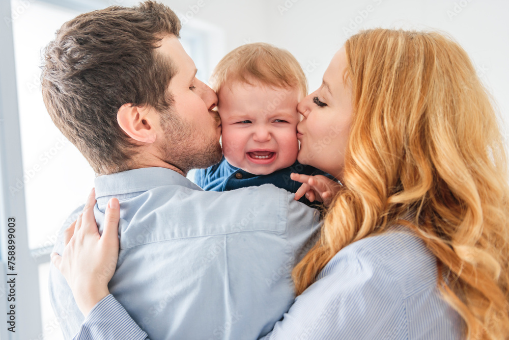 young beautiful family couple consoling the baby boy on gray studio