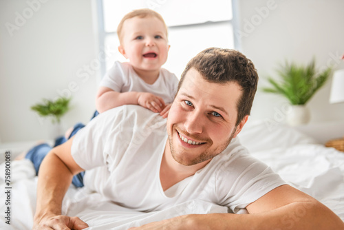 bearded father holding baby boy on bed, fatherhood and love