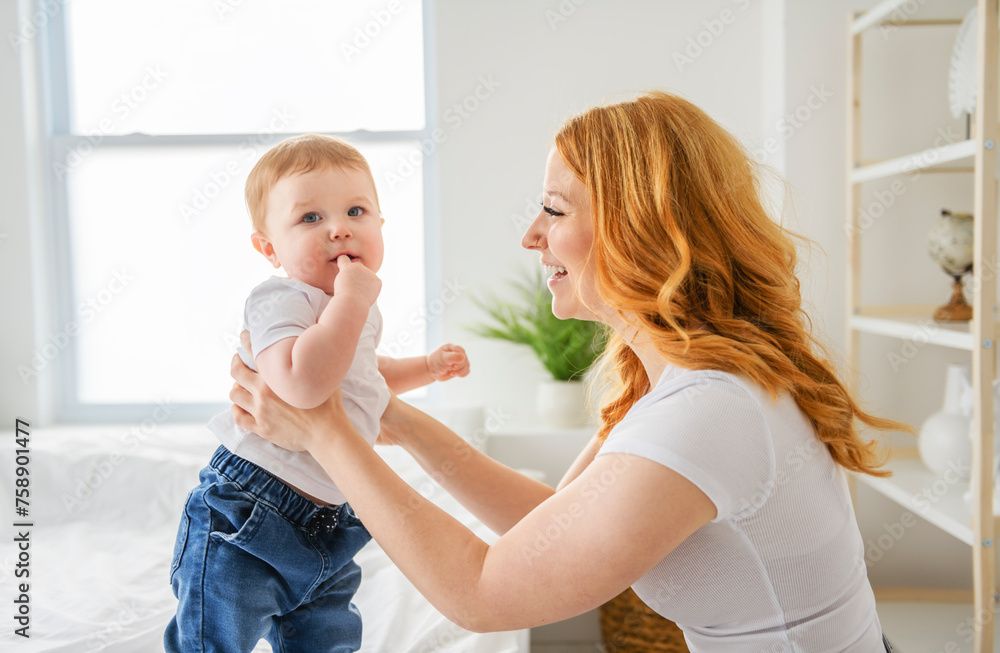 Mother and baby boy on bed, having great moment together on white bedroom Mother and baby boy on bed, having great moment together on white bedroom