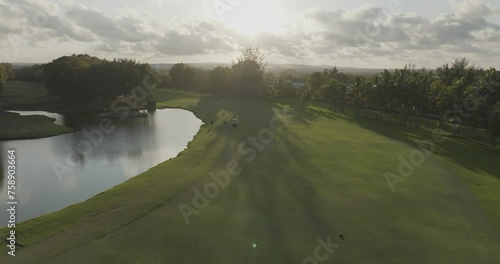 Aerial view of Golf Course with lush green grass and people playing golf at sunset, Constance, Flacq, Mauritius. photo