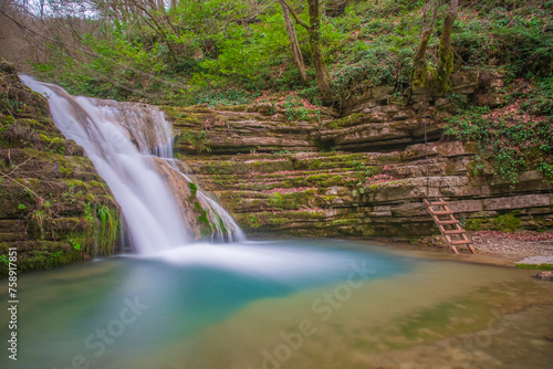 Fototapeta Naklejka Na Ścianę i Meble -  The idea of being in nature and the waterfall flowing through the trees decorated with autumn colors the rocks calmness peace and happiness