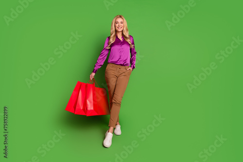 Full length photo of gorgeous positive person hold shop bags empty space isolated on green color background