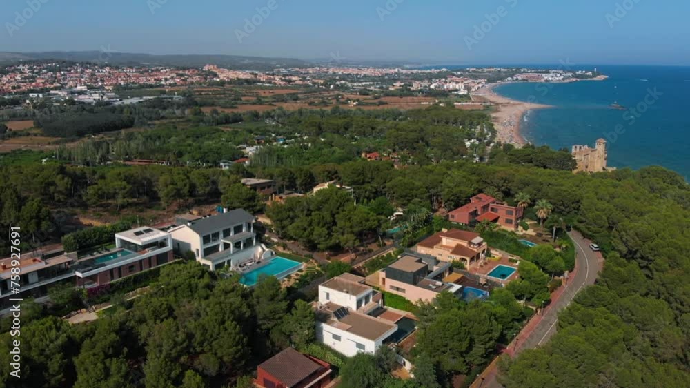 A beautiful aerial view of a coastal residential area featuring buildings, trees, and natural landscape next to the ocean under a clear sky A beautiful aerial view of a coastal residential area featuring buildings, trees, and natural landscape next to the ocean under a clear sky