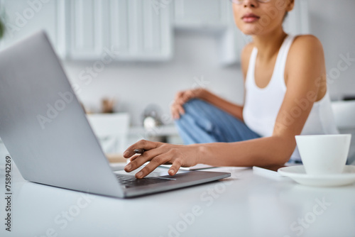 cropped african american freelancer working from home remotely on her laptop  cup of coffee