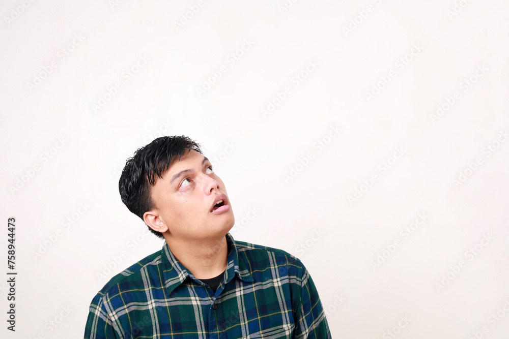 Adult Asian man thinking about something with eye looking up. Isolated on white with copyspace Adult Asian man thinking about something with eye looking up. Isolated on white with copyspace