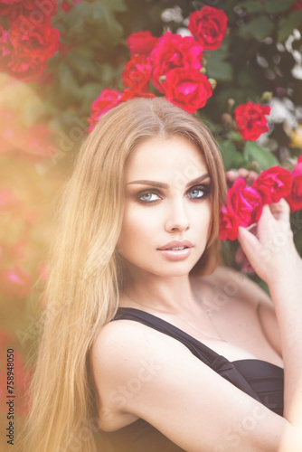 Beautiful fashionable woman with red lips makeup posing outdoor, in blooming rose garden.