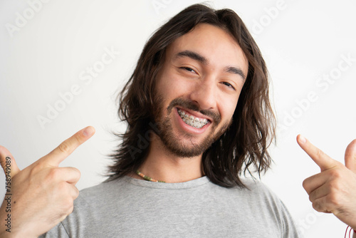 smiling young latin man pointing his fingers at his braces