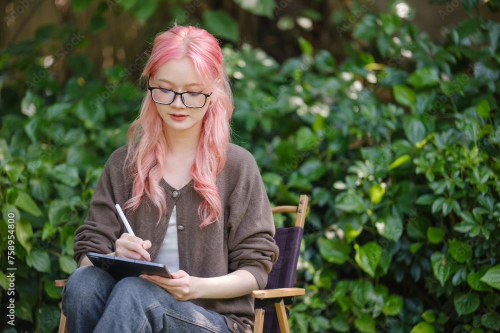 Cute pink hair girl drawing on digital tablet in garden, Woman Doing Freelance Work in Garden, woman with digital tablet with artwork. Cute pink hair girl drawing on digital tablet in garden, Woman Doing Freelance Work in Garden, woman with digital tablet with artwork.