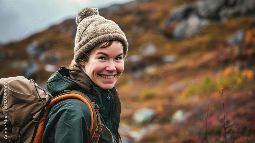 A woman with a hat and backpack on a mountain trail smiles happily A woman with a hat and backpack on a mountain trail smiles happily