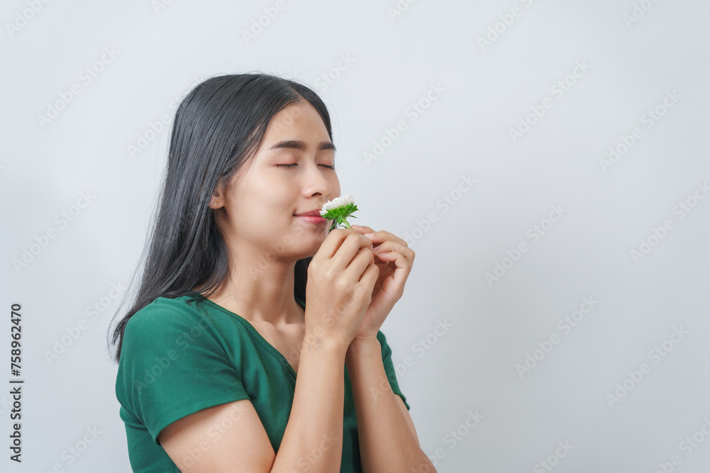 Beautiful young Asian woman in green t-shirt inhales the fragrance of white chrysanthemum flowers, isolated on white background. Beautiful young Asian woman in green t-shirt inhales the fragrance of white chrysanthemum flowers, isolated on white background.