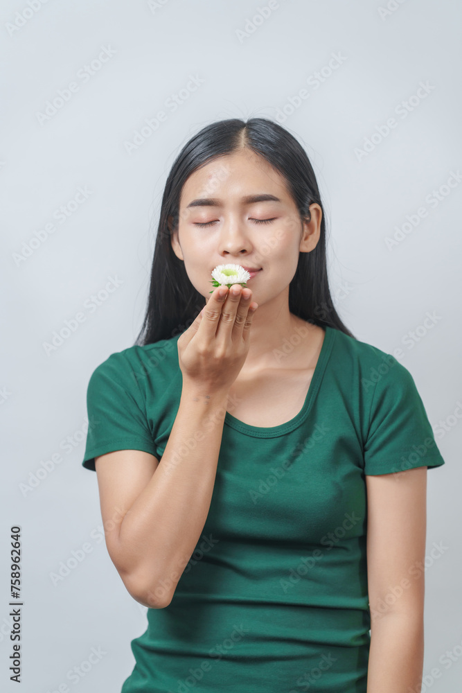 Beautiful young Asian woman in green t-shirt inhales the fragrance of white chrysanthemum flowers, isolated on white background. Beautiful young Asian woman in green t-shirt inhales the fragrance of white chrysanthemum flowers, isolated on white background.