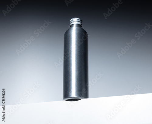 Metallic silver bottle with screw cap without label. Medicine and cosmetics. On white base with gray background (ID: 758963226)