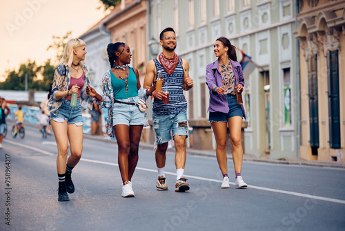 Happy man and his female friends walking down street while going to summer music festival.