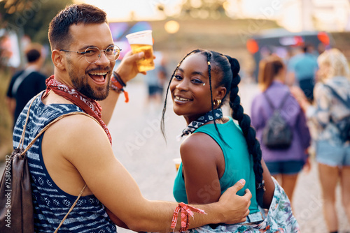 Cheerful multiracial couple going on summer music festival and looking at camera.
