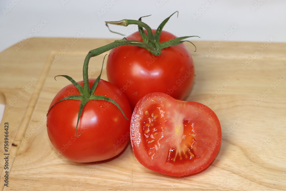 red round tomato on a wooden cutting board red round tomato on a wooden cutting board