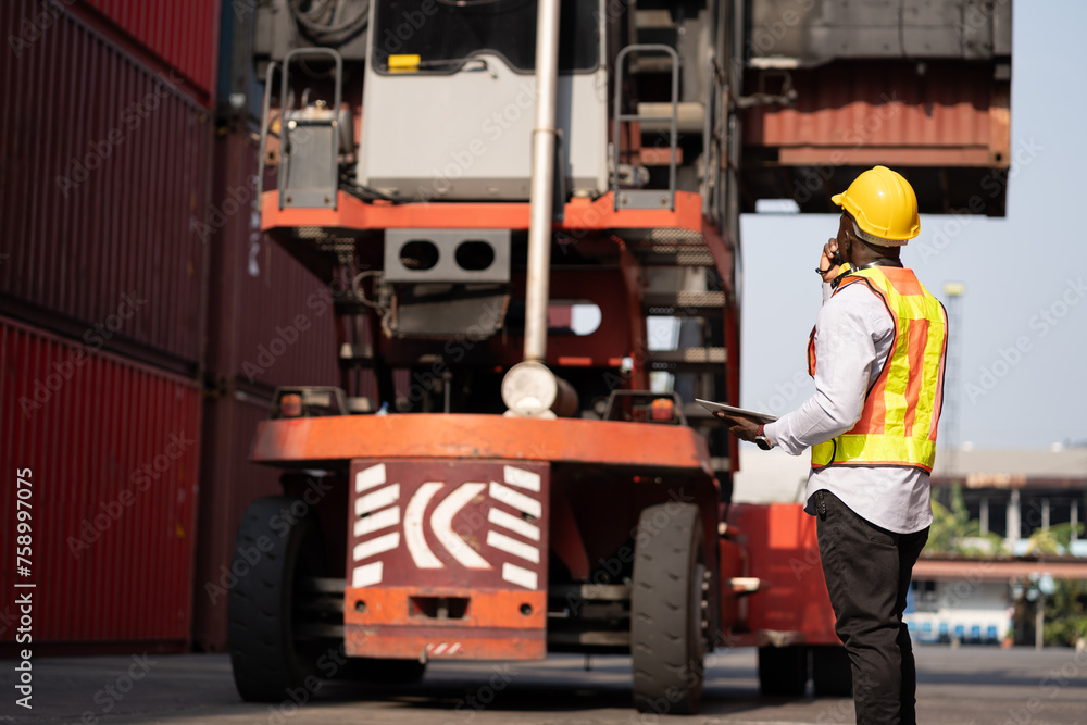 African logistic engineer man worker or foreman working direct driver forklift container at container site African logistic engineer man worker or foreman working direct driver forklift container at container site