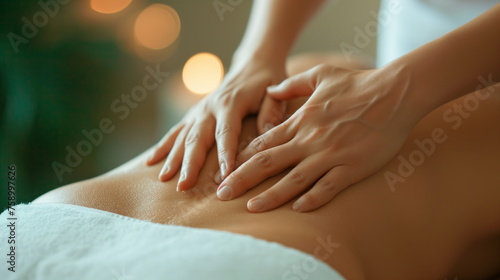 woman lies on a massage table while a massage therapist performs a back massage using professional techniques in a spa setting photo