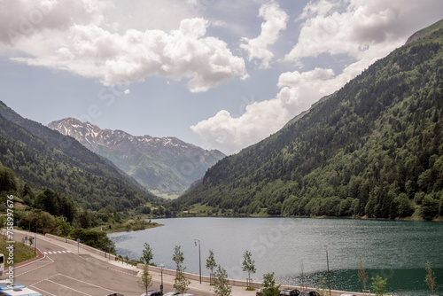 an asphalt road next to a lake in the mountains. a lake in the Pyrenees Mountains. The concept of automobile tourism in the mountains. convenient parking in a tourist location in the mountains. photo