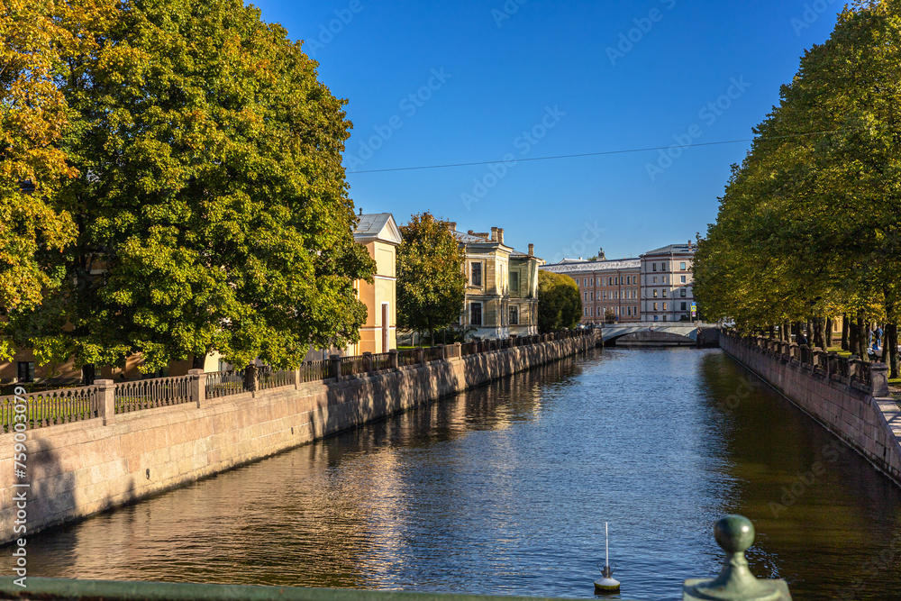 A picturesque view of the canal, river in the historical town, calm canal with historic houses and green trees under blue sky