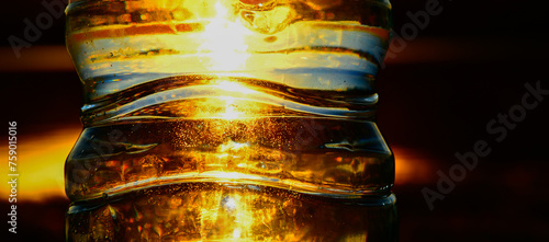 Parte de botella de agua de plástico con el sol del atardecer captado por detrás, Abstracta  photo