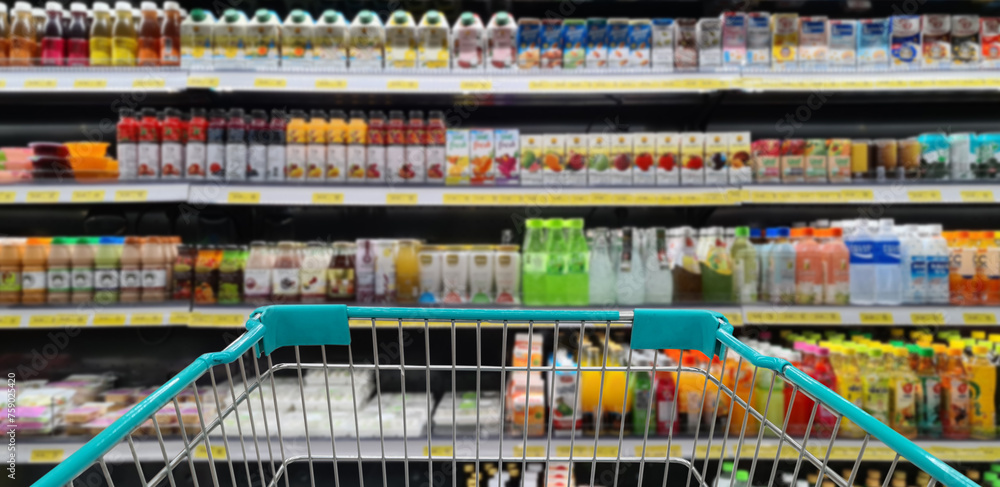 Green shopping cart with blurred image of beverage on shelf in background. (Selective focused at shopping cart).