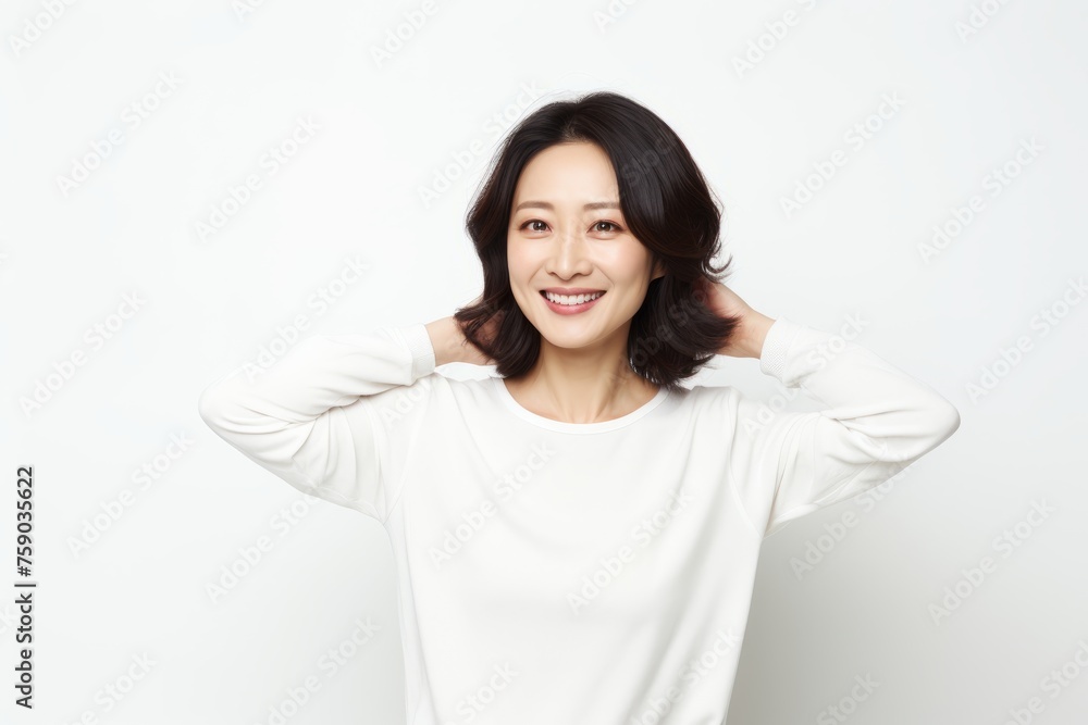 happy young asian woman smiling and touching her neck over white background happy young asian woman smiling and touching her neck over white background