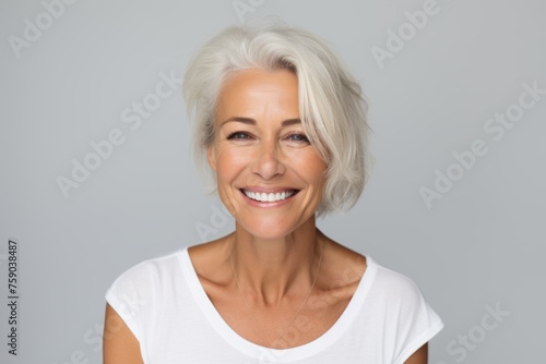 Portrait of beautiful mature woman smiling at camera, over grey background