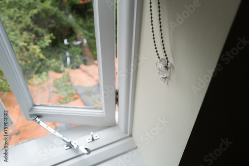 Tablou pe pânză Shallow focus of a metal chained roller blind rope seen attached the side wall of a first floor cottage window