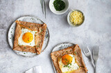 Homemade buckwheat crepes. Galettes bretonnes with cheese and fried egg on a gray background. Traditional French cuisine.