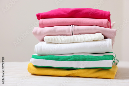Stack of folded clothes on table against beige background