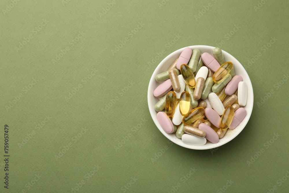 Different vitamin pills in bowl on olive background, top view. Space for text Different vitamin pills in bowl on olive background, top view. Space for text